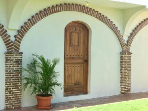 een boog met een houten deur en een plant bij Hotel Yamilí in Punta Cana