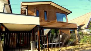 une maison en bois avec une clôture devant elle dans l'établissement Hospedaje Las Animas Valdivia, à Valdivia