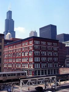 a large brick building with a train in a city at HI Chicago Hostel in Chicago