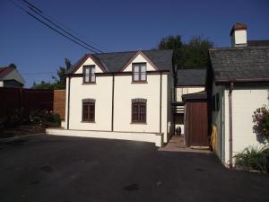 een wit huis met een oprit en een garage bij Carpenters Cottages in Llanishen