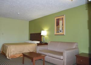 a hotel room with a bed and a chair at Americana Inn - Henderson in Henderson