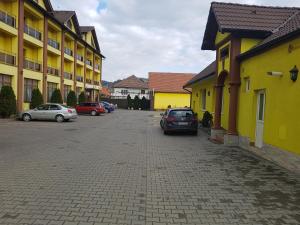 un aparcamiento con coches estacionados al lado de los edificios en Hotel Edelweiss, en Mediaş