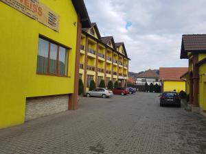 un edificio amarillo con coches estacionados en un estacionamiento en Hotel Edelweiss, en Mediaş