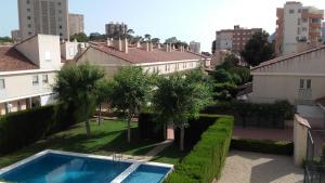 uma piscina num quintal com árvores e edifícios em la casa gris em Alicante