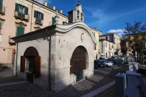 a small white building with a tower on a street at Angelino Home in Sulmona