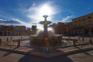 a fountain in a city with the sun behind it at Angelino Home in Sulmona