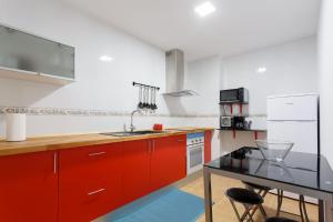 a kitchen with red cabinets and a black table at 1- Apartamento Playa Canido in Malpica