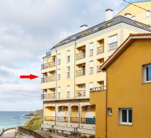 a building next to the ocean with a red arrow at 1- Apartamento Playa Canido in Malpica