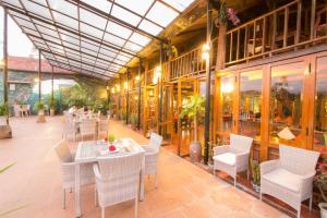 a restaurant with white chairs and tables and windows at Phong Nha Lake House Resort in Phong Nha