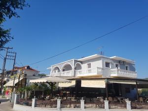 a white building with a balcony and tables and chairs at Mojo modern apartment in Alikanas
