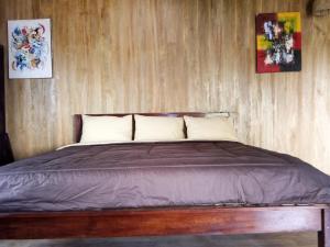 a bed in a room with a wooden wall at Rock Pool Homestay in Huu