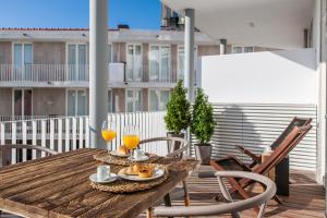 a wooden table and chairs on a balcony with orange juice at Casas da Baixa - Terracos das Olarias Pool in Lisbon