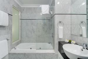 a white bathroom with a tub and a sink at MacArthur Chambers in Brisbane
