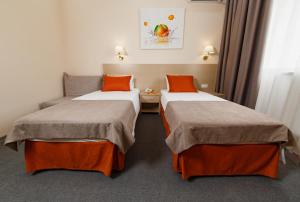 two beds in a hotel room with orange pillows at Mandarin Hotel in Anapa