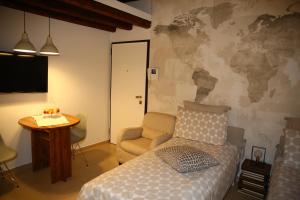 1 dormitorio con 1 cama, 1 silla y TV en Masone Home, en Módena