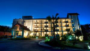 a large building with a palm tree in front of it at Bintang Flores Hotel in Labuan Bajo