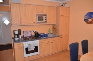 a kitchen with wooden cabinets and a stove and microwave at Ferienwohnung Fischerhafen 14/Guent in Ostseebad Karlshagen