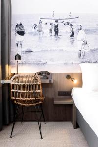 a bedroom with a desk and a chair in front of a beach at Hotel Albert Plage in Knokke-Heist