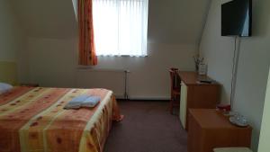 a bedroom with a bed and a desk and a window at Hotel Melody in Oradea