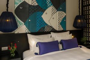 a bedroom with a bed with purple pillows and a painting at Sol An Bang Beach Resort & Spa in Hoi An