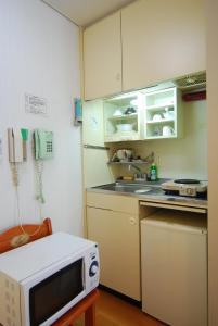 a kitchen with white cabinets and a microwave at Weekly Green In Namba in Osaka