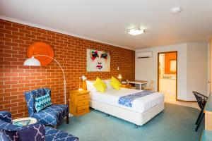 a bedroom with a bed and a brick wall at Yackandandah Central in Yackandandah