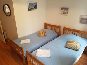 2 Einzelbetten in einem Schlafzimmer mit blauer Bettwäsche in der Unterkunft Granville hyper centre in Granville