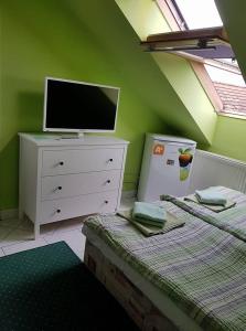 a green room with two beds and a television on a dresser at Penzión KORMOŠ in Štúrovo