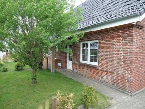 a red brick house with a tree in the yard at Ferienhaus Janik in Friedrichskoog