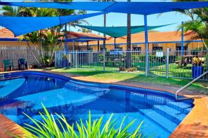 a swimming pool with a blue umbrella next to a house at Yamba Twin Pines Motel in Yamba