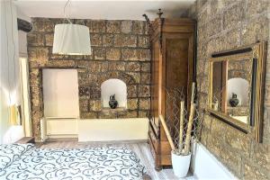 sypialnia z kamienną ścianą z łóżkiem i lustrem w obiekcie iRoom Civita w mieście Bagnoregio