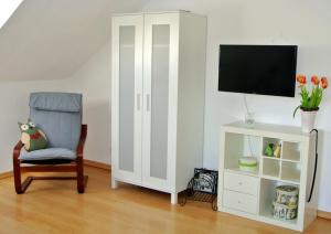 a room with a chair and a tv and a cabinet at Ferienwohnung Voelkel mit Dachterrasse in Trier