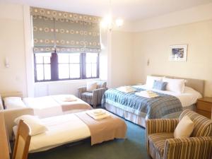 a hotel room with two beds and two chairs at Pentland Lodge House in Thurso