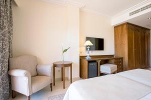 a bedroom with a bed and a chair and a television at Hipotels Barrosa Garden in Chiclana de la Frontera