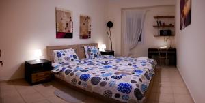 Schlafzimmer mit einem Bett mit einer blauen und weißen Bettdecke in der Unterkunft Patras Palm Tree in Patras