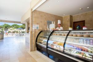 a chef standing behind a counter in a bakery at Hipotels Barrosa Garden in Chiclana de la Frontera