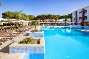 a swimming pool with lounge chairs and a hotel at Hipotels Barrosa Garden in Chiclana de la Frontera