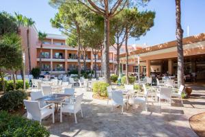 um pátio exterior com mesas, cadeiras e árvores em Hipotels Barrosa Garden em Chiclana de la Frontera