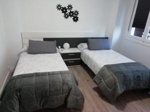 a bedroom with two beds and a table and a window at La Barrica de Gran vía 43 en el centro de Logroño in Logroño