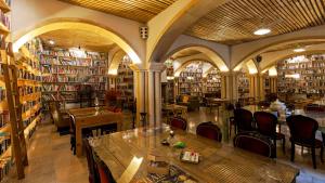a library with tables and chairs and bookshelves at The Literary Man Obidos Hotel in Óbidos