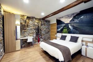 1 dormitorio con 1 cama extragrande y pared de piedra en Urdaibai Etxea, en Ea