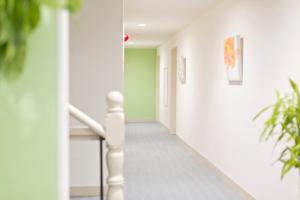 a hallway with white walls and stairs with plants at Shin-Okubo City Hotel in Tokyo