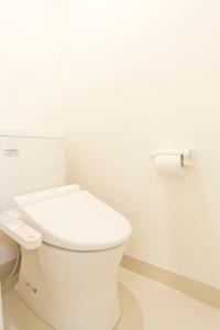 a white bathroom with a toilet and a roll of toilet paper at Shin-Okubo City Hotel in Tokyo