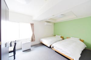 two beds in a room with a window at Shin-Okubo City Hotel in Tokyo