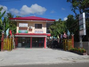 a building with a red roof and a gate at La Fela Pension House in Oslob