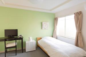 a bedroom with a bed and a tv and a window at Shin-Okubo City Hotel in Tokyo