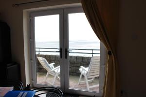 a sliding glass door with chairs on a balcony at B2 Waterfoot Apartment in Newcastle