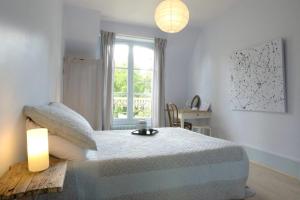 a bedroom with a bed with a lamp and a window at Chambres d'hôtes du Jardin Francais in Ermenonville