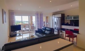 a living room with a black couch and a kitchen at Panorama Apartment in Lagos