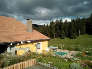 une maison jaune avec une piscine dans une cour dans l'établissement La Dernier (La cote-aux-fées) Suisse, à La Côte-aux-Fées